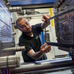 person working on large piece of manufacturing equipment